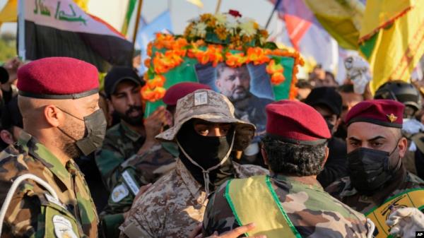 Fighters from the Popular Mobilization Forces carry the coffin of a commander from the Kataib Hezbollah paramilitary group, Wissam Muhammad Sabir Al-Saadi, who was killed in a US airstrike, in Baghdad, Iraq, Feb. 8, 2024.